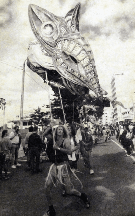 black and white image of a large taniwha puppet operated by many puppeteers
