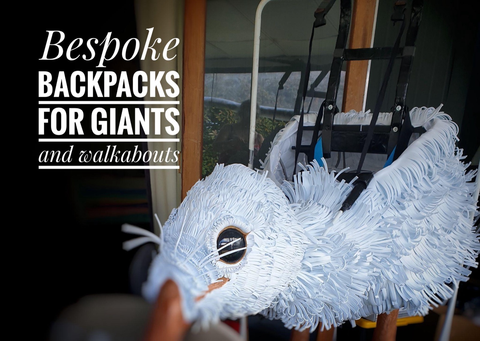 A fluffy white giant puppet bird strapped into a carrying-backpack frame